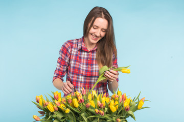 Cheerful young woman florist holding box of tulips.