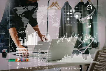 Fashion designer talking mobile phone and using laptop with digital tablet computer in modern studio