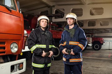Obraz premium Fireman (firefighter) in action standing near a firetruck. Emergency safety. Protection, rescue from danger.