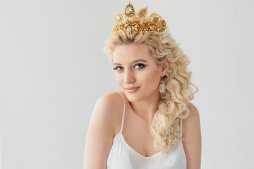 Beauty portrait of attractive blond girl with curly hair and a beautiful headband over white...