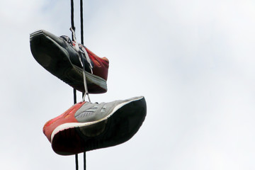 Two old sneakers hang on electric wires. The concept is time for a vacation