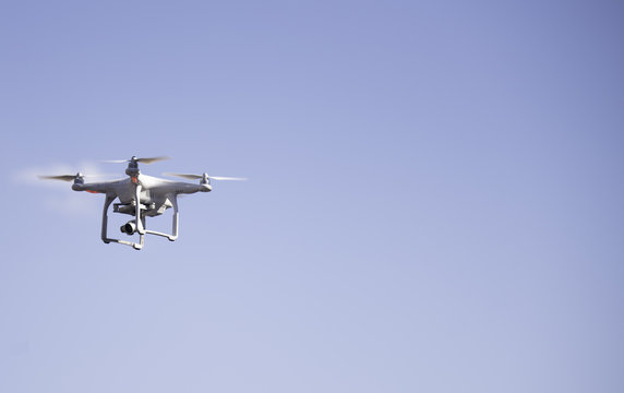 Flying Quadcopter Drone in the blue sky background. Free copy text space.