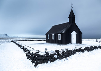 View of Budir church on snow covered landscape against clear sky