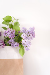 Lilac bouquet in craft bag. Portrait