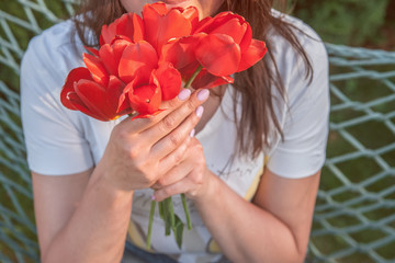 Portrait of happy female florist with bunch of red tulips looking at camera