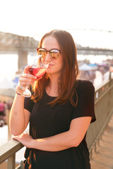 Woman drinking a wine in the city during a sunset. Glass of red wine. Concept of free time in the city and drinking alcohol. 