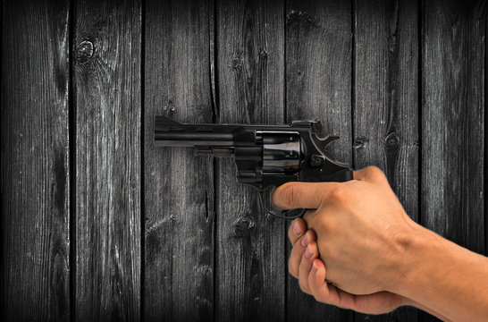 Gun in hand against the  wood background . crime.