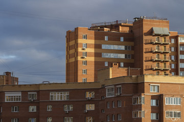 Жилой дом на фоне грозового неба. Дома из красного кирпича. Спальный район. Современный город. Стены и окна.
