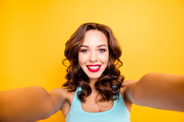 Self portrait of trendy charming girl with modern hairdo shooting selfie on front camera isolated...