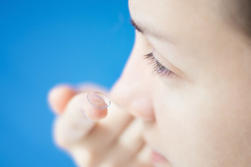 Young woman putting contact lens in her eye