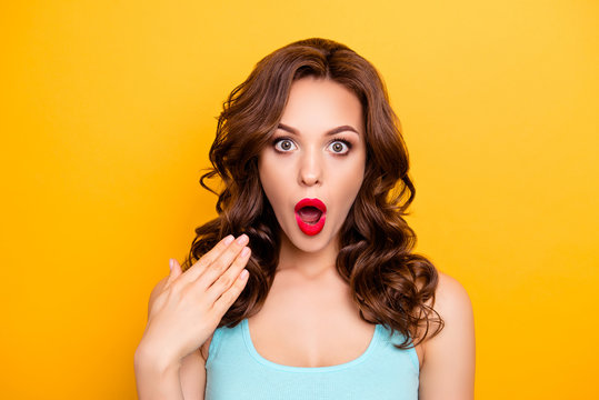 Portrait of shocked impressed woman with unexpected unbelievable reaction gesturing palm looking at camera with wide open eyes mouth isolated on yellow background