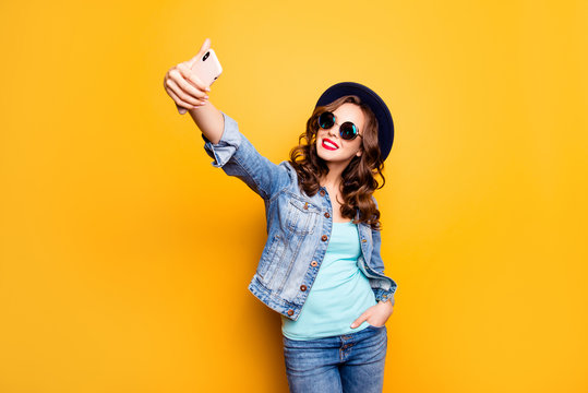Portrait of charming pretty blogger cool coquette holding hand in pocket of pants shooting selfie on front camera of smart cell phone having video-call isolated on yellow background