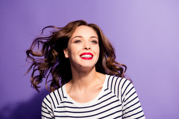 Portrait of positive toothy girl with beaming white smile enjoying sun light wind blow looking away having red pomade flying hair isolated on violet background