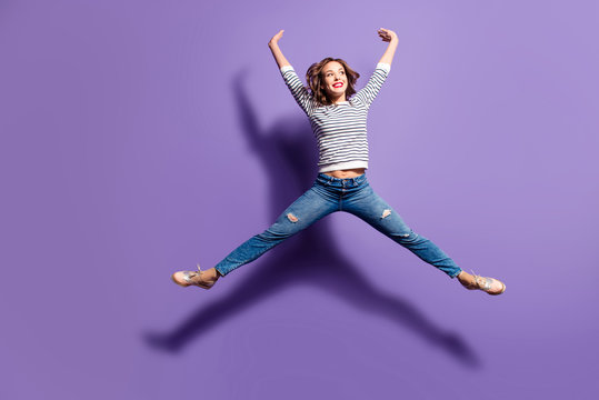 Portrait of funny comic girl jumping in the air making star figure looking away isolated on violet background full of energy powerful people concept