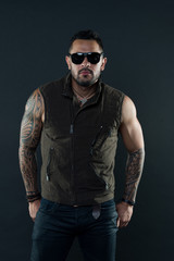 Fashion style and trend. Tattoo model with beard on unshaven face. Bearded man with tattoo on strong arms. Tattooed man with biceps and triceps. Fashion macho in trendy sunglasses