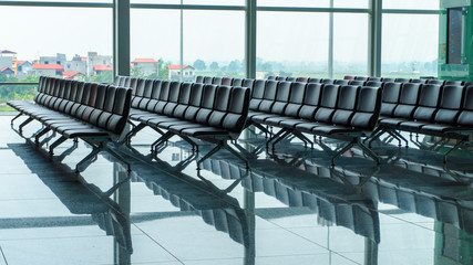 Raw of empty seats in airport waiting area near gate and big window