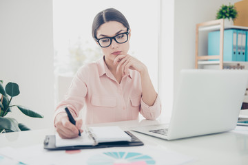 Portrait of busy smart concentrated confident elegant classic woman sitting in modern office making notes in notepad, organizing her day week, writing down ideas date of conference