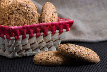 homemade oat cookies with sunflower seeds in and near red checkered basket on black table