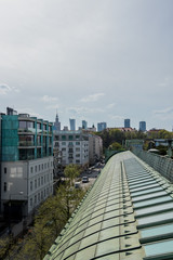 urban landscape with people cars and apartments and other buildings seen from the roof of a modern building on an early spring day