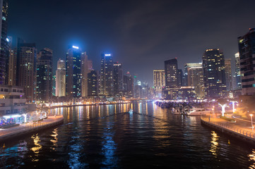 Fototapeta premium Dubai, United Arab Emirates - December 26, 2017: water canal on Dubai Marina skyline at night. Residential towers with lighting. Architecture or structure and design. Vacation and wanderlust