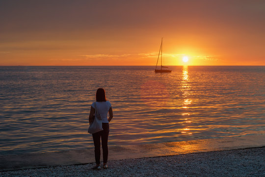 Junge Frau betrachtet den Sonnenuntergang am Meer
