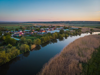 Small cozy village on the river side. Beautiful landscape with a bird's eye view on a summer evening