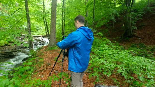 traveler photographer shoots beautiful sunset on the shore of a mountain river