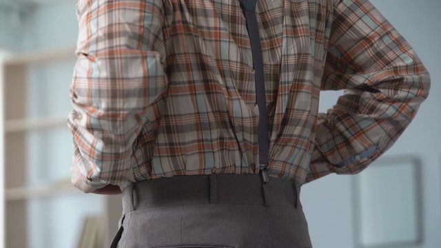 Man pulling up braces over retro shirt, wearing old-fashioned clothes for job