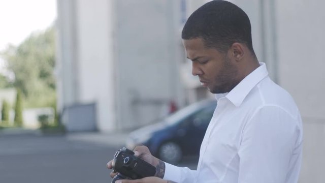 African American photographer takes a photo with his camera outdoor at city background