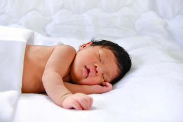 Newborn Concept. Newborn babies are sleeping in a bed. The baby is in the white bedroom.