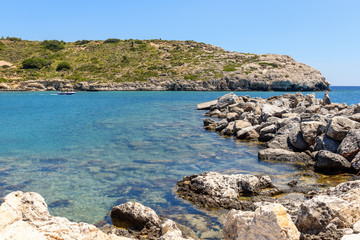 Fototapeta na wymiar Rocky coast of Kolymbia bay in sunny day. Rhodes island, Greece