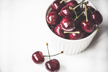 Fresh ripe cherries in ceramic bowl. Isolated on white background, close up. Healthy food concept.