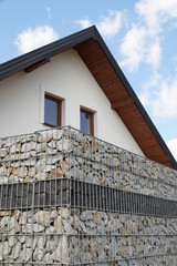 A house surrounded by a modular gabion fence