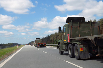 A convoy of military trucks while passing the highway