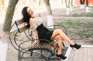 Obraz premium Beautiful Girl, brunette with red lips. Spring , shooting in the Park . sitting on the bench