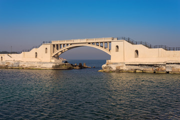 Bridge in the sea at Montazah park with calm sea and clear sky at sunrise time, Alexandria, Egypt