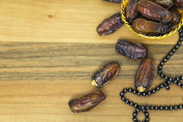 Date fruits in the plate and rosary on the wooden background for eleven month sultan Ramadan...