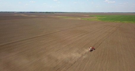 Obraz premium Tractor cultivates the field, spring works on farmlands. Photo from the drone
