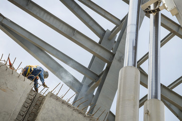 Welder soldering metal girders in a structure high above 