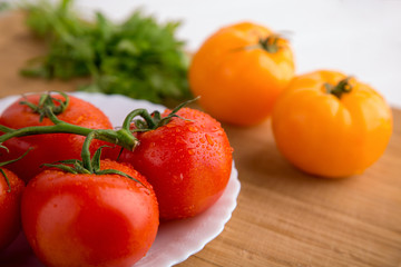Fresh red and yellow tomatoes close up on a wooden board at a white backgound