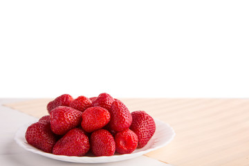 Fresh red strawberry on a white plate on a white isolated background shot from the front with copy space