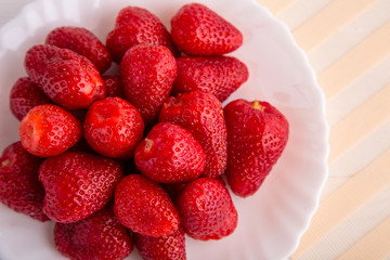 Fresh red strawberry on a white plate close up shot from above