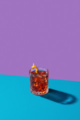 Negroni IBA cocktail, with gin, bitter, vermouth, in pop contemporary style, colorful, dark background.