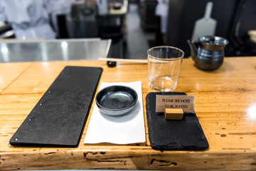Japanese traditional style, interior asian sushi wooden bar counter restaurant sign, menu, bowl, glass, napkin setting empty nobody closeup