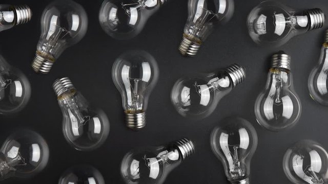 Flashing light bulb among a lot light bulbs on black desk. Idea concept