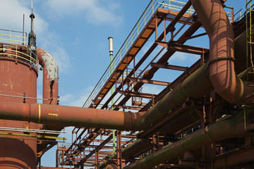 Abandon rough rust red painted structure of steel pipelines construction and metal tanks in industrial manufacturing  plant .