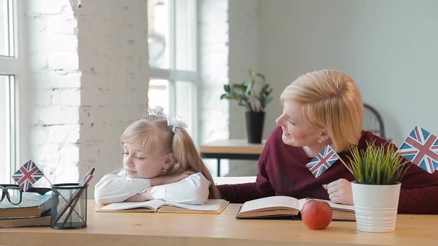 Kind teacher trying to interest bored student, cute girl with pigtails looking into window, indoor shot during english lesson