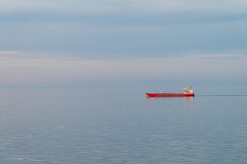 Red freighter sailing on a calm blue sea