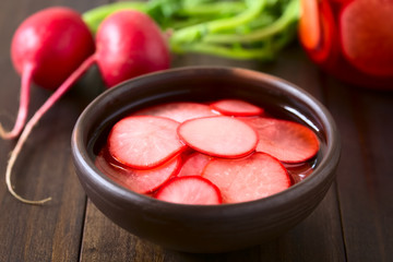 Fresh radishes cut in thin slices pickled in red wine vinegar with sugar and salt, photographed with natural light (Selective Focus, Focus on the front of the radish slice on the top)