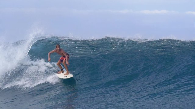 SLOW MOTION: Athletic man on fun summer holiday rides a big crystal clear wave on a perfect sunny day in the summer. Extreme sportsman surfing near a popular surf spot rides and epic Cloudbreak wave.